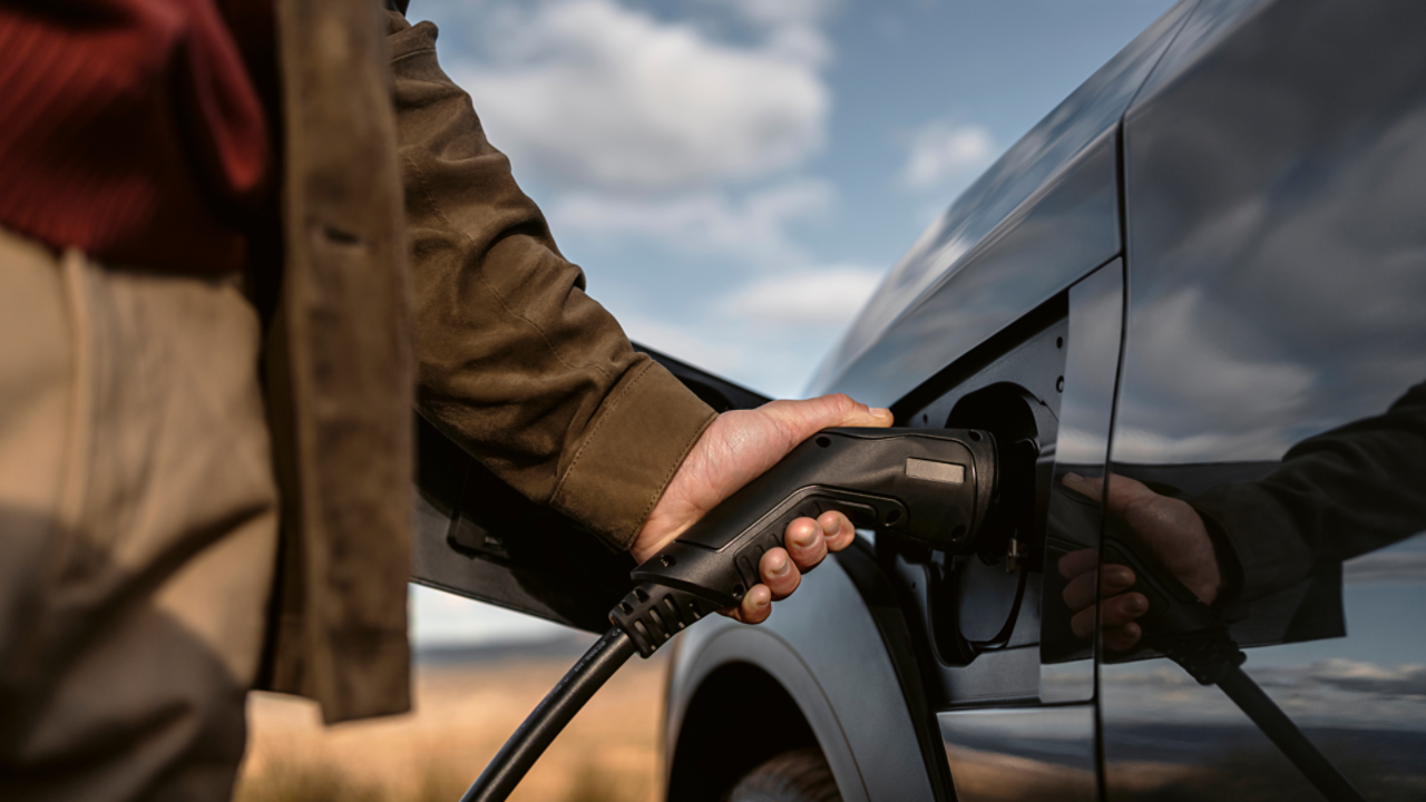 A person plugging in a charging socket into a Lexus